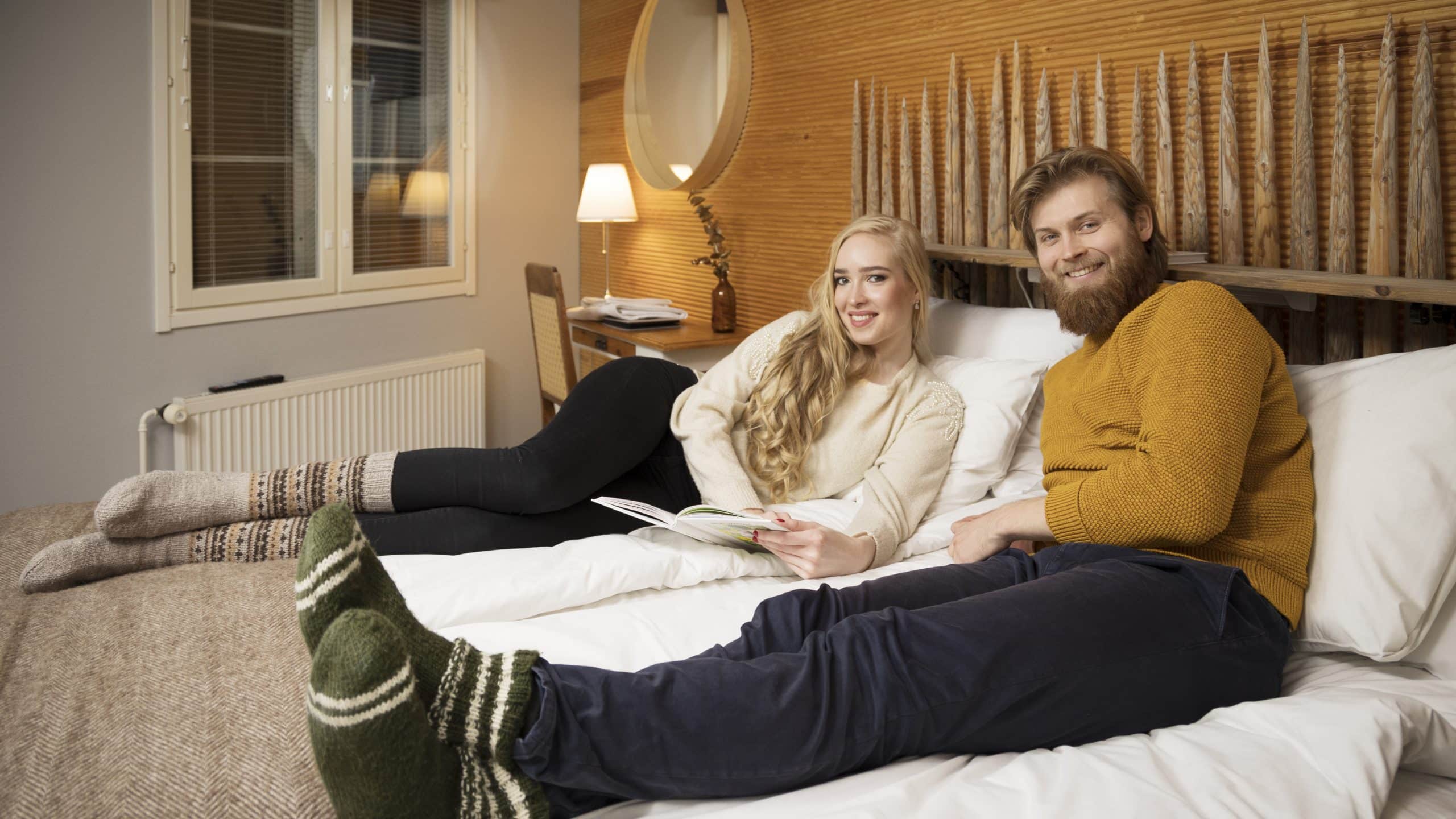 Henkilöt majoitushuoneen sängyllä