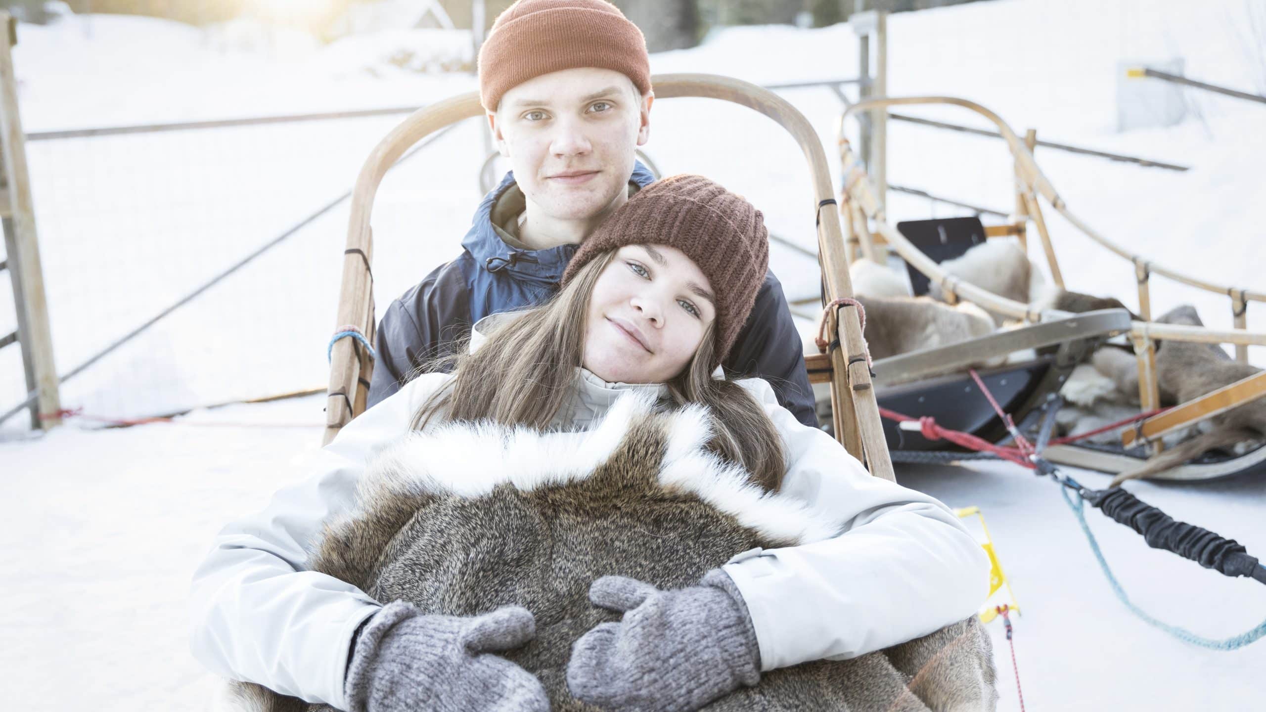 Kaksi henkilöä koiravaljakon kyydissä