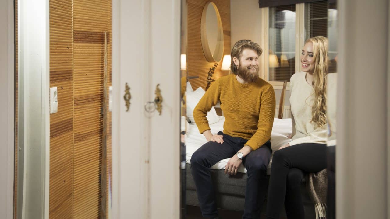 Pariskunta istuu sängyllä hotellihuoneessa