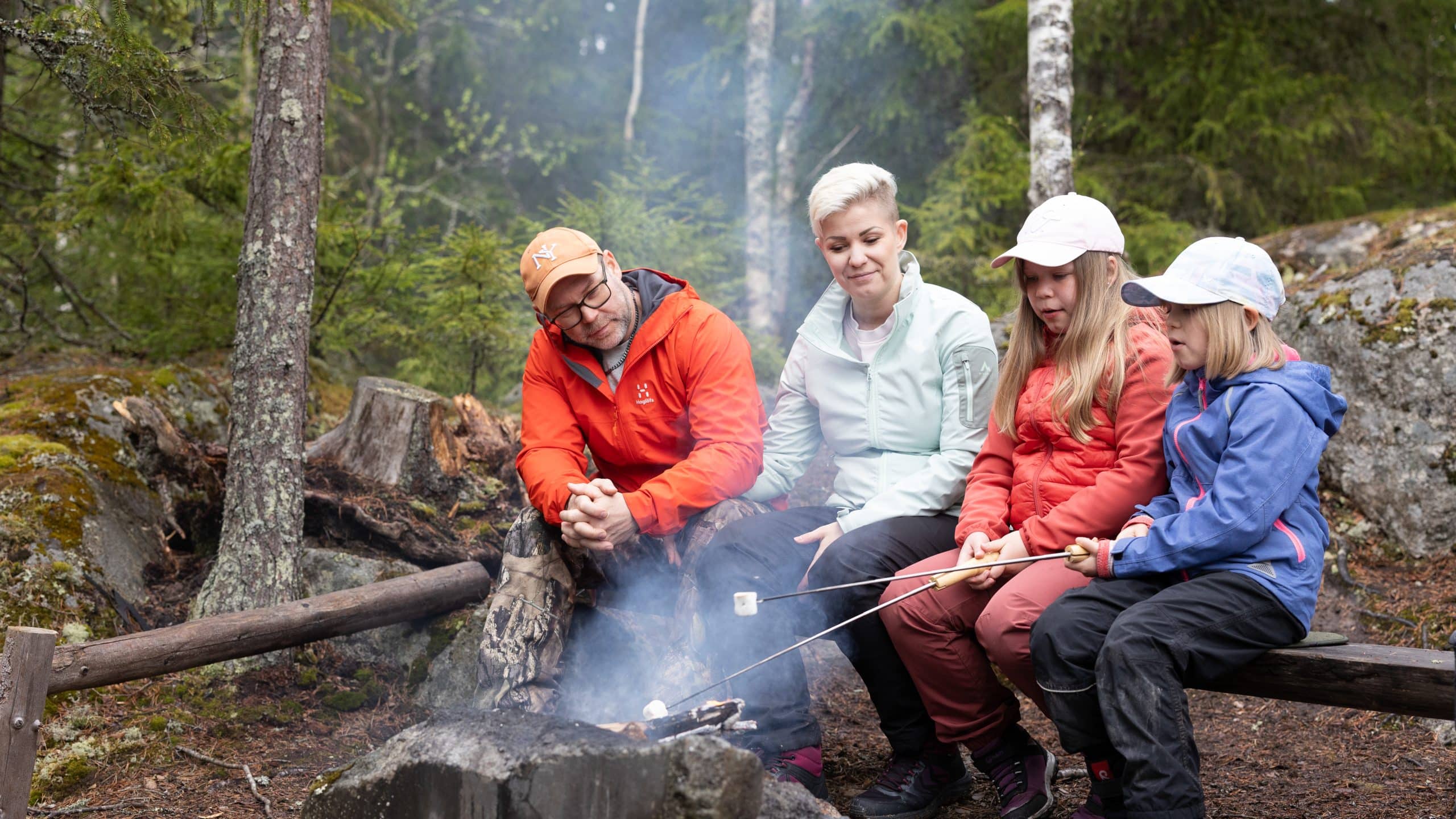 Perhe paistamassa vaahtokarkkeja nuotiolla.