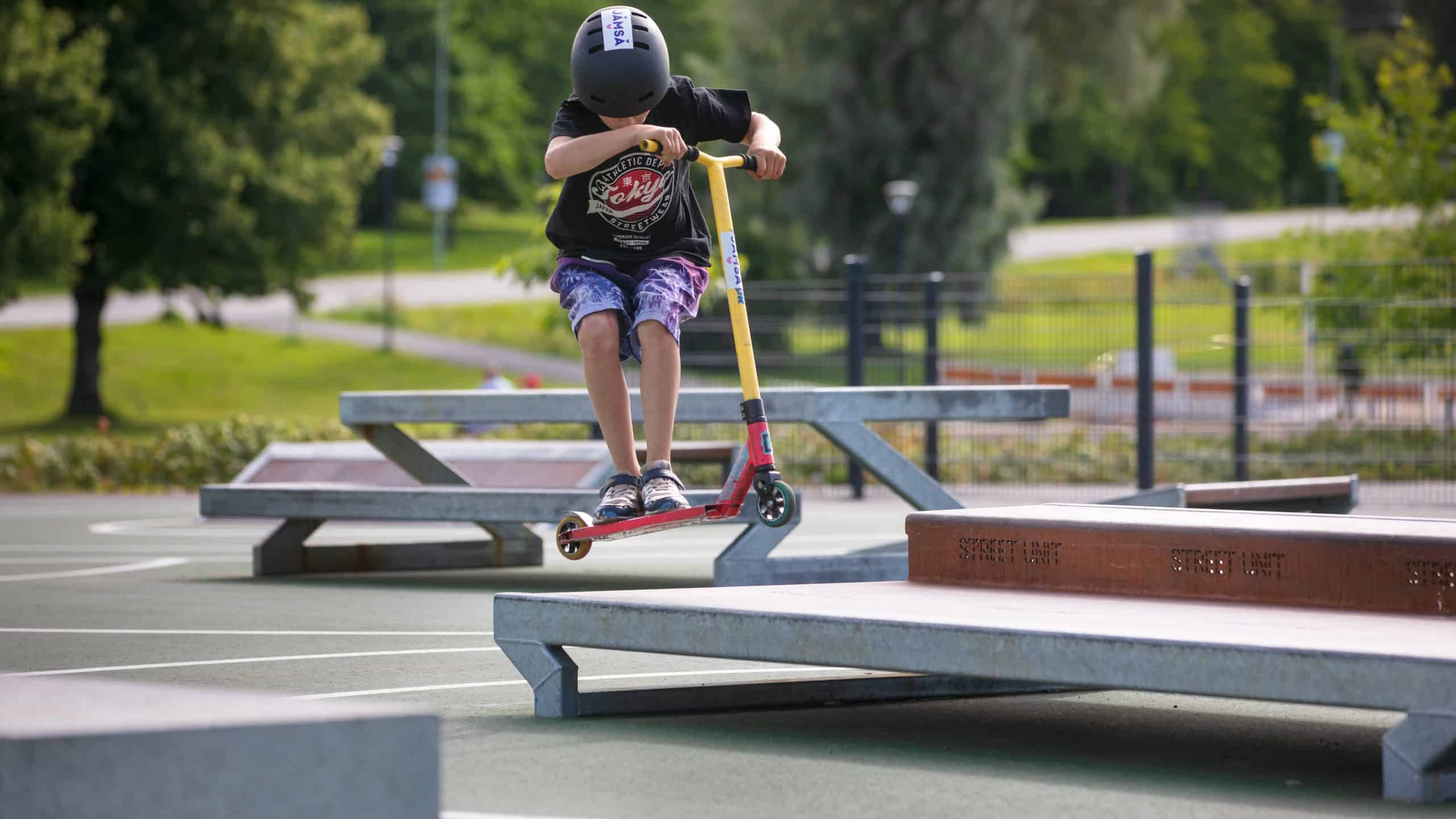 Lapsi hyppää potkulaudalla korokkeen päälle