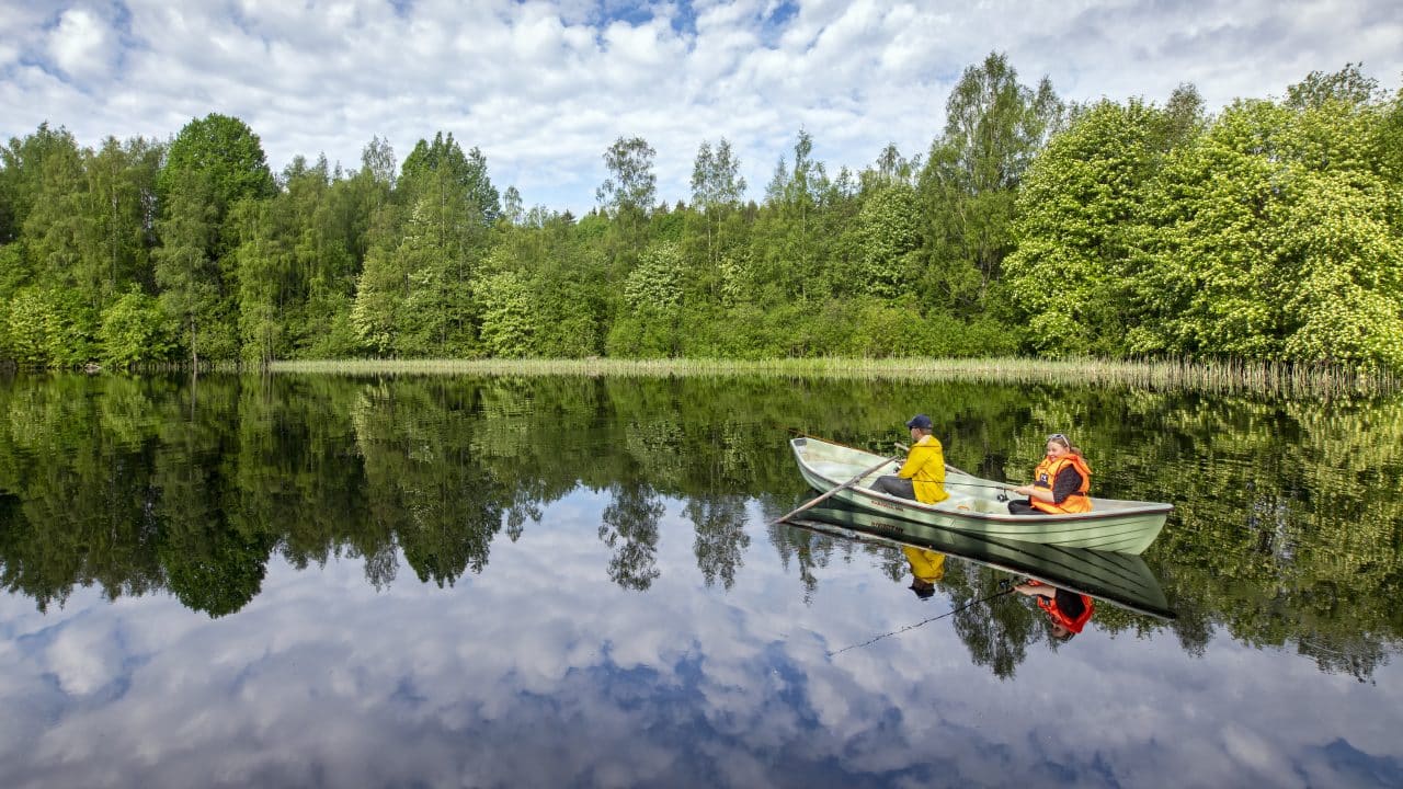 Soutuvene, jonka kyydissä on kaksi veneilijää tyynellä joella