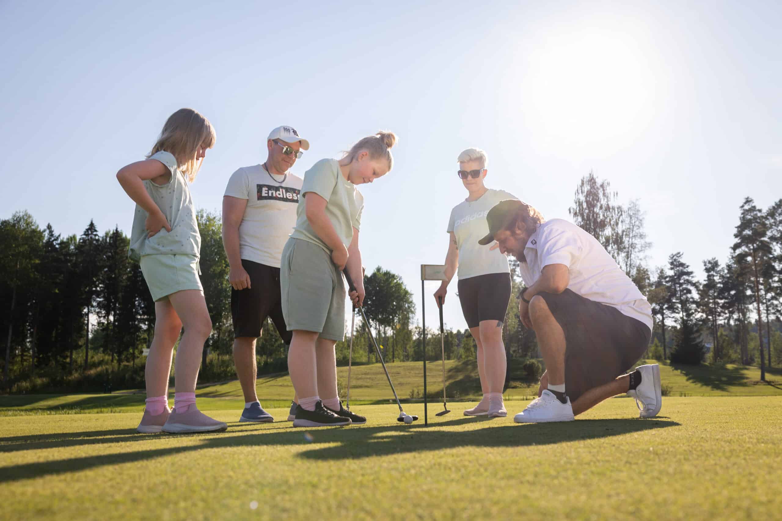 Perhe pelaa golfia Himos Golfin viheriöllä