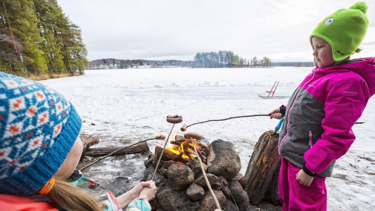 Retkeilijäseurue makkaranpaistossa järvenjään laidalla