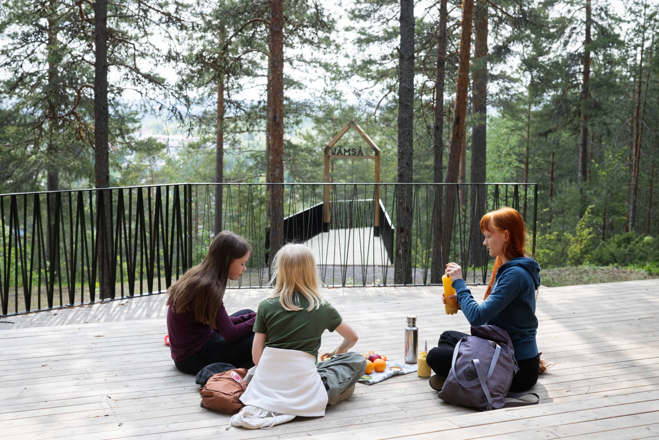 Kolme retkeilijää syö eväitä Hartusvuoren-Pukinvuoren laavulla