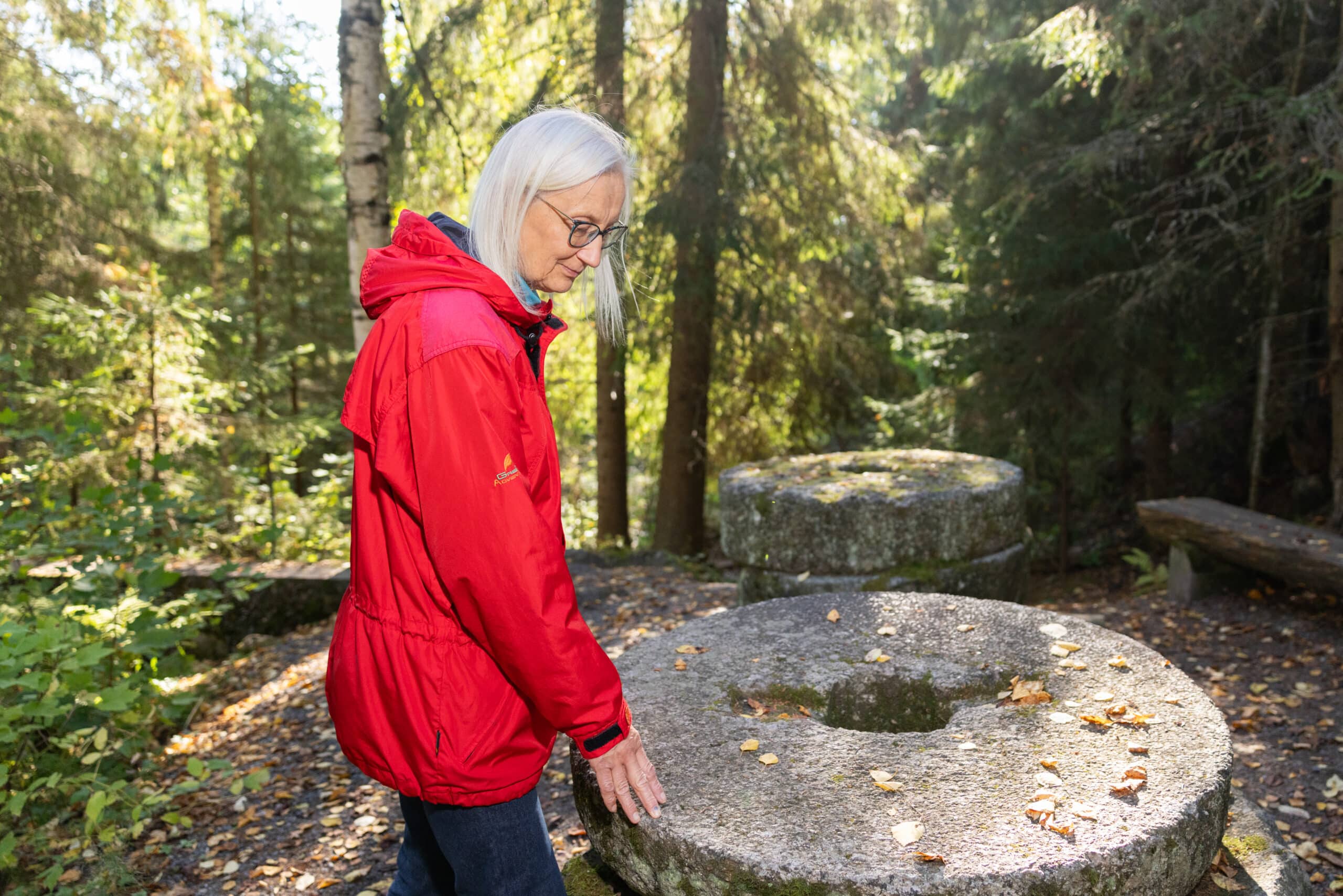 Nainen tunnustelee myllykiviä Juveninkoskella