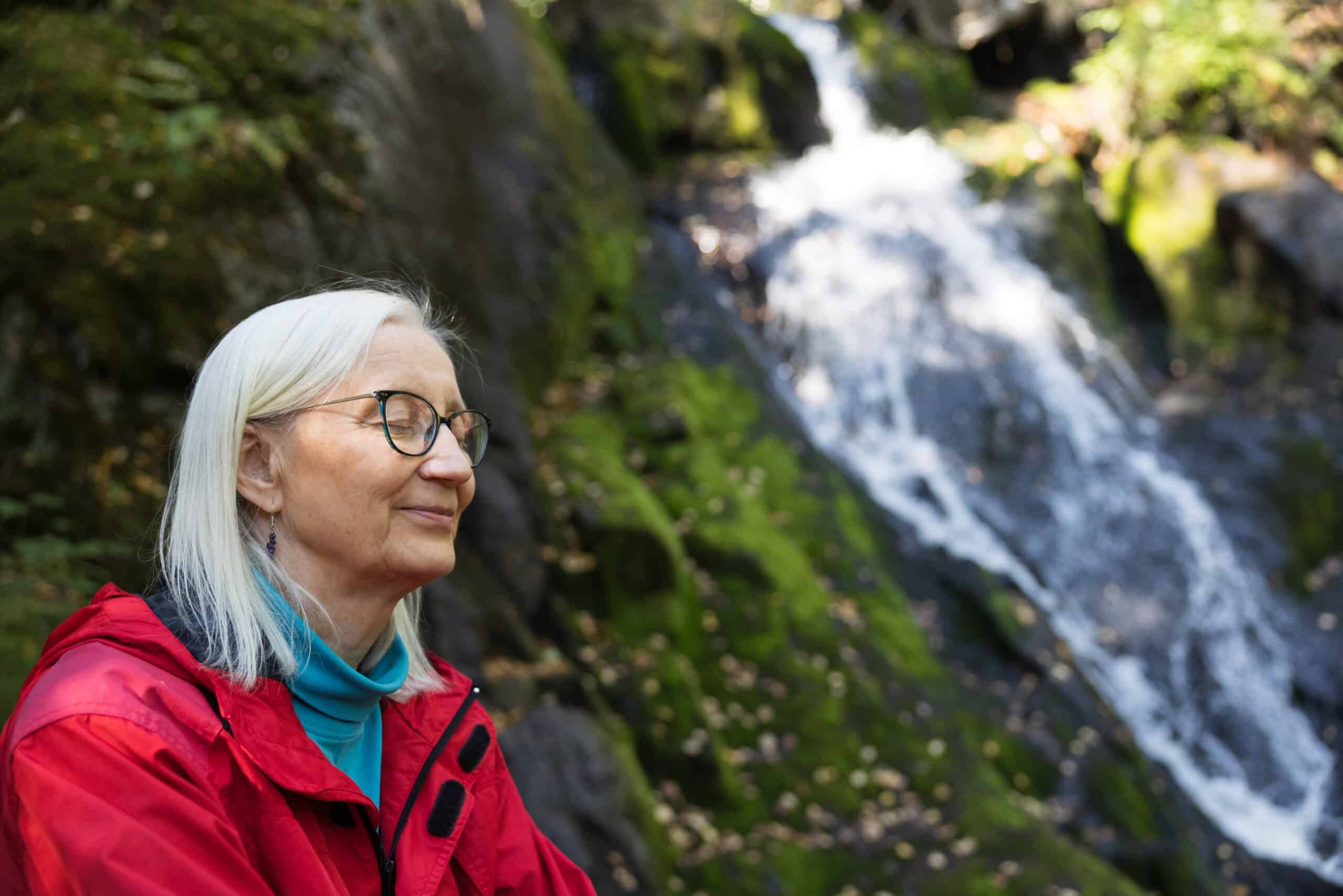 Nainen istuu silmät kiinni Juveninkoskella