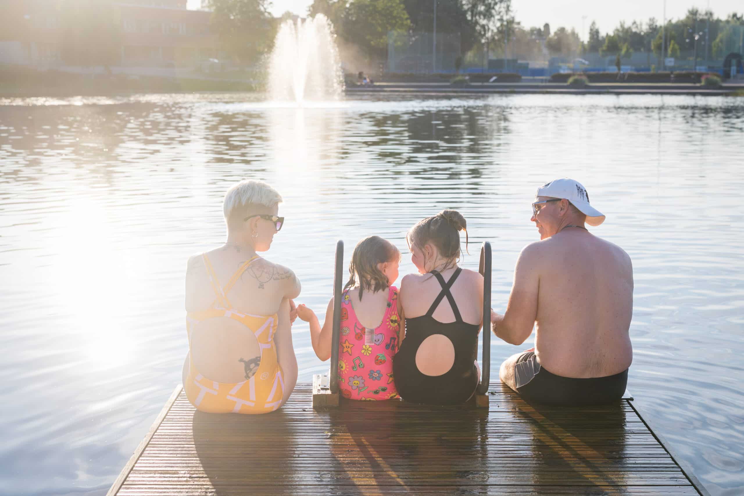 Nelihenkinen perhee istuu laiturilla maauimalalla Jämsässä.