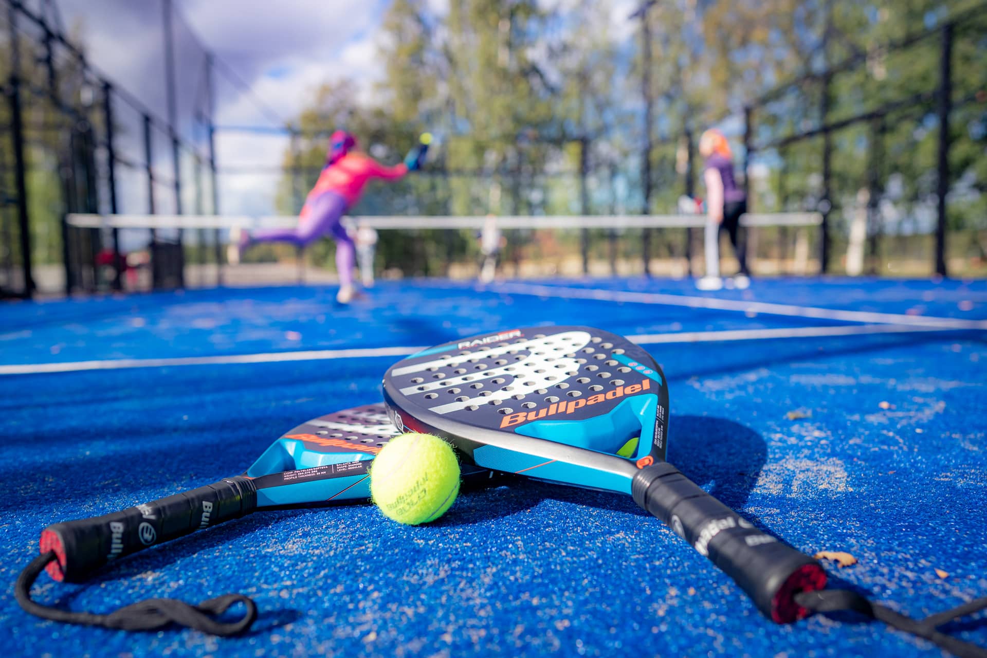 Naiset pelaavat padelia ulkokentällä