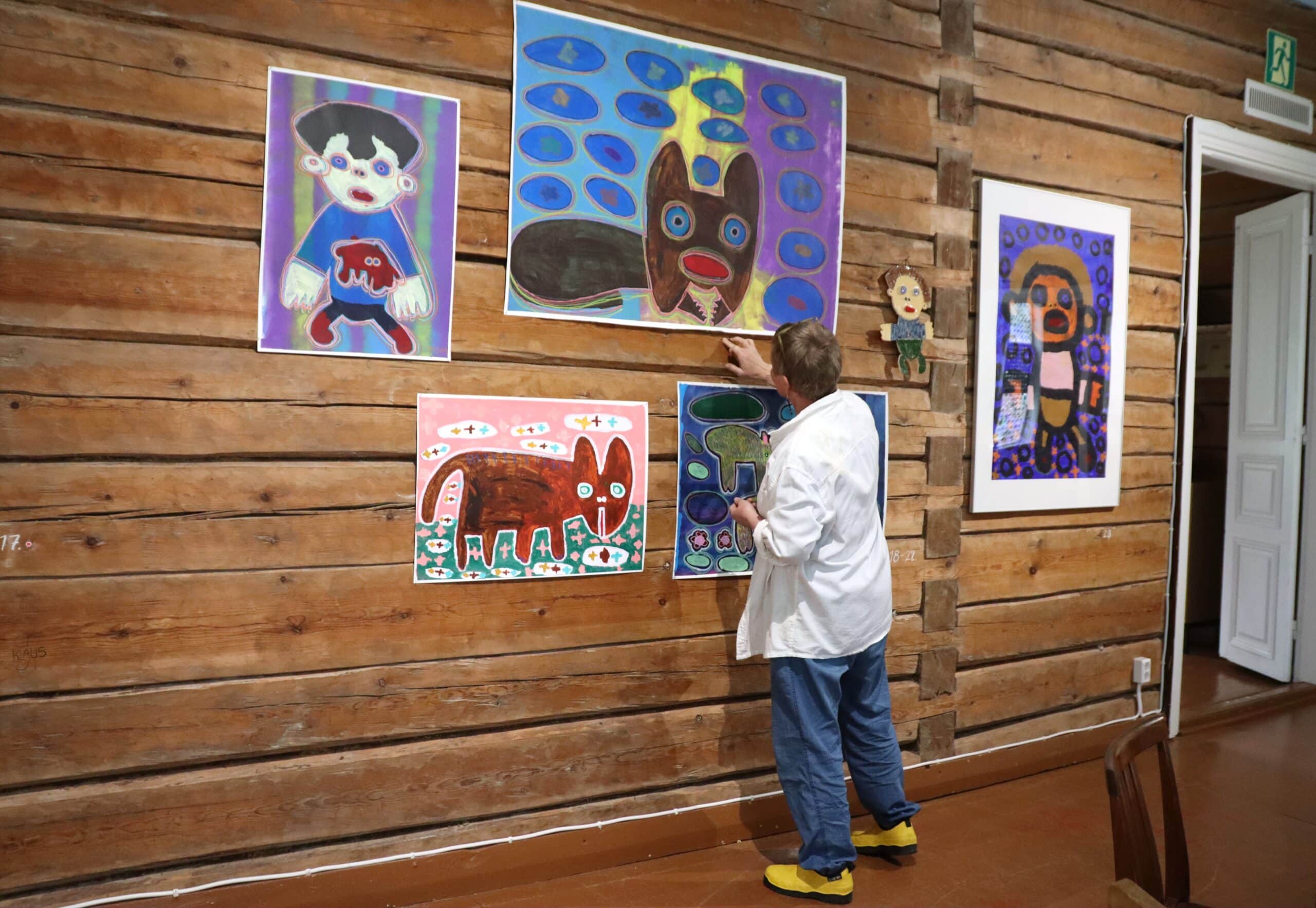 Nainen ripustaa maalauksia seinälle