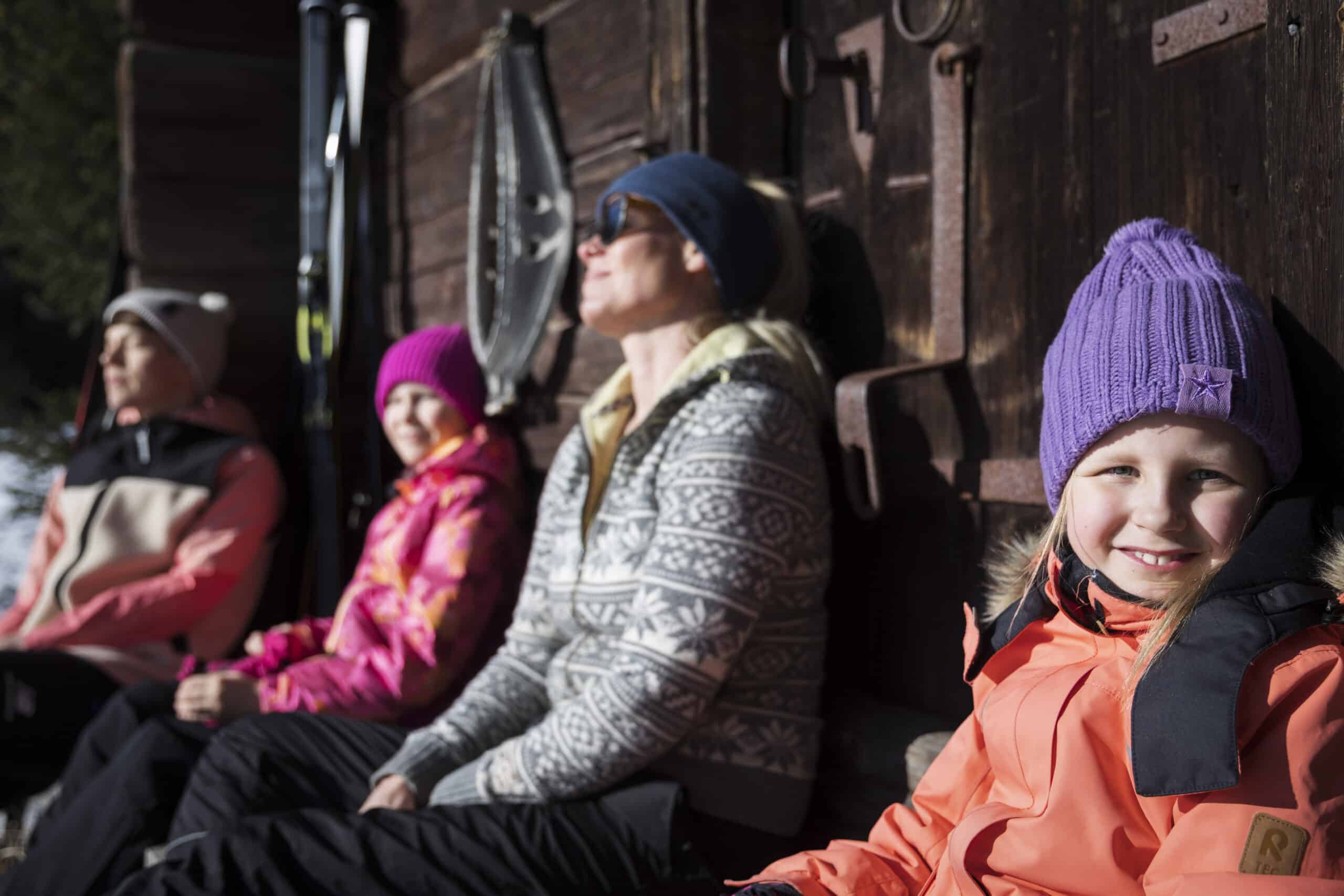 Neljä henkilöä nauttii auringosta talvella