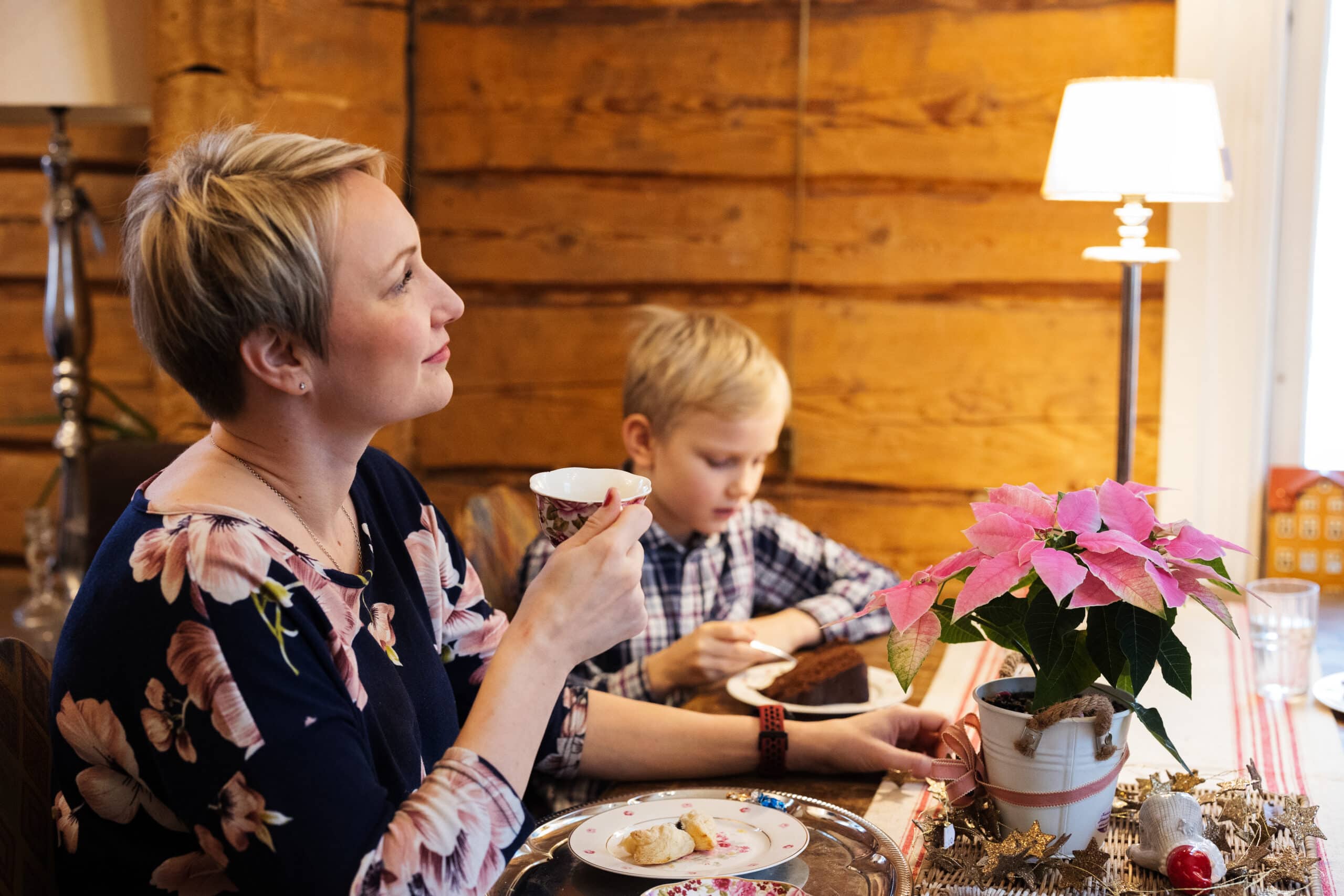 Nainen juo kahvia kahvilassa, vieressä lapsi