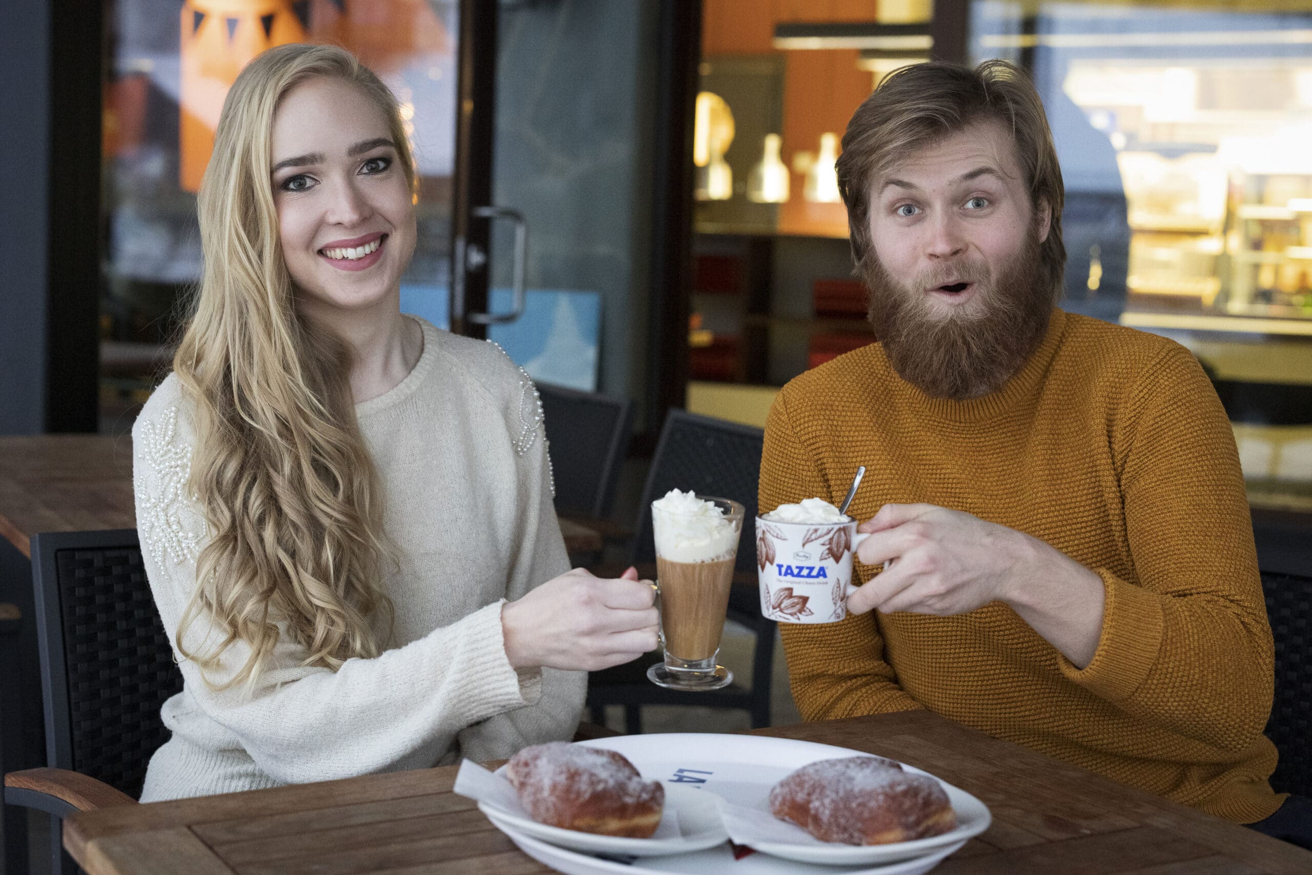 Kaksi henkilöä skoolaa kahvikupeilla kahvilassa