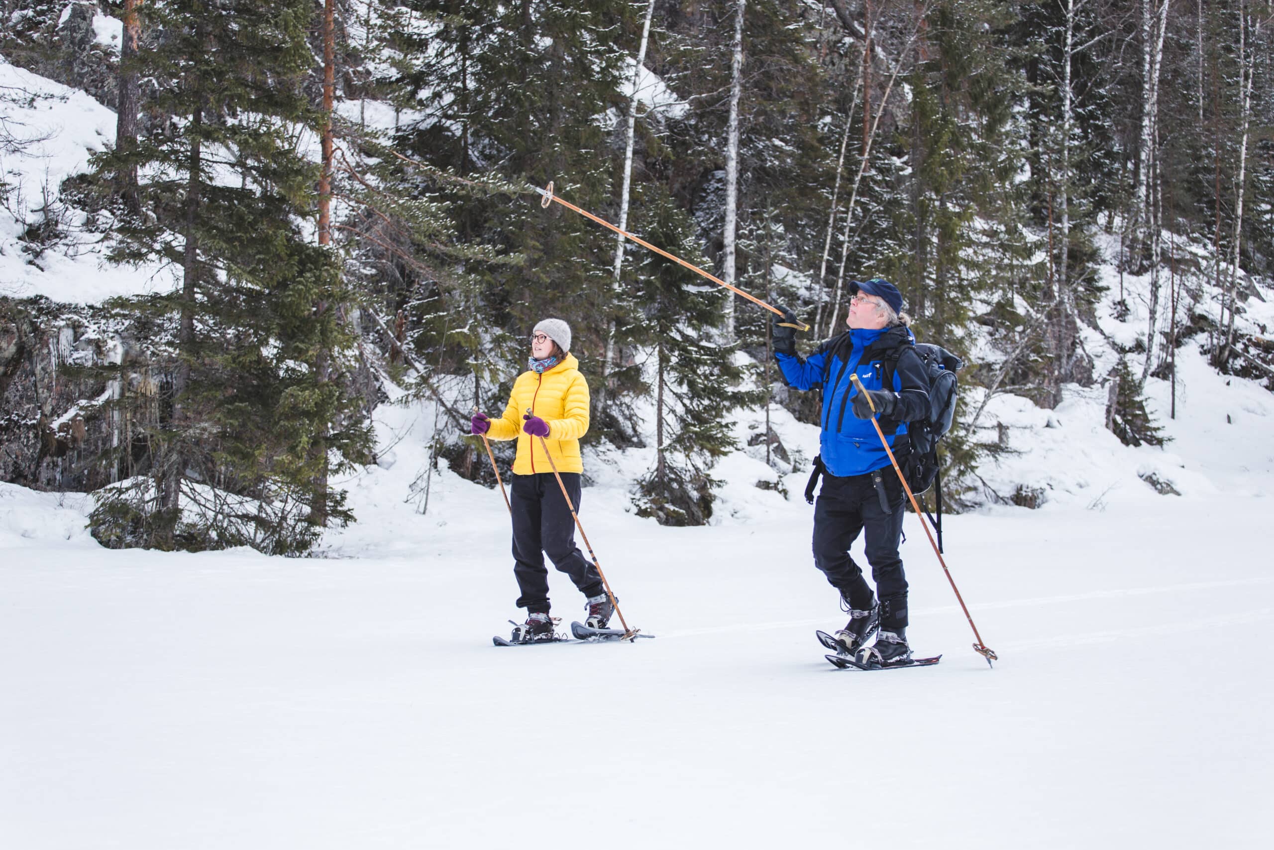 Kaksi lumikenkäilijää talvisessa maisemassa