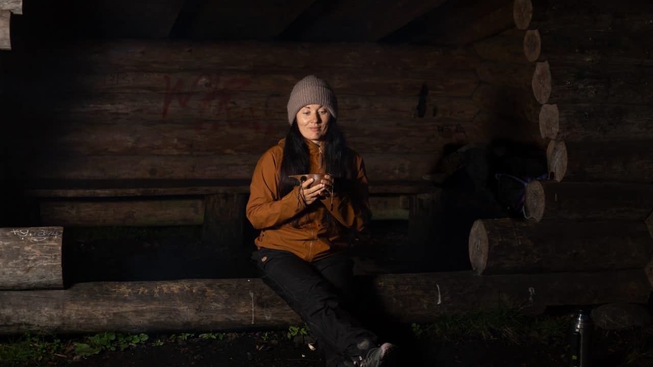 Retkeilijä syömässä leipää laavulla illalla