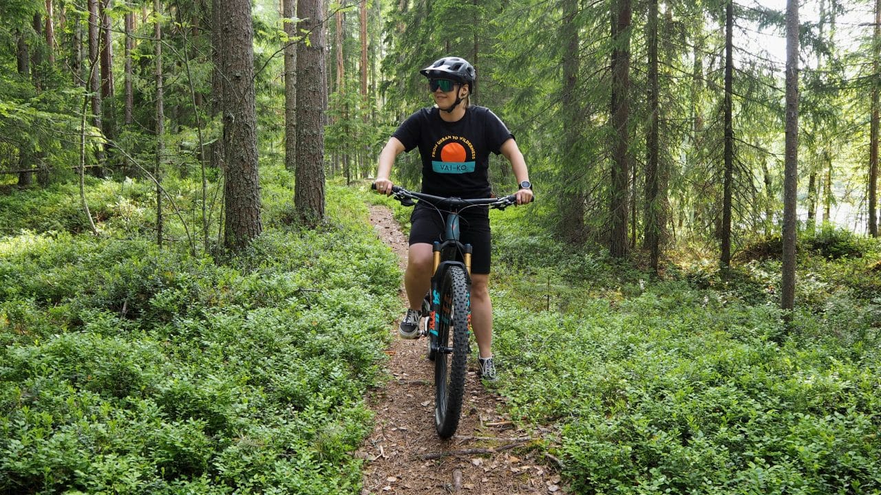 Maastopyöräilijä kesäisellä neulaspolulla