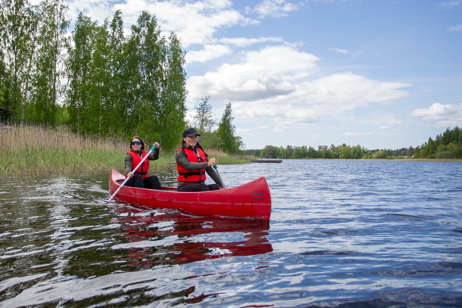 Kaksi henkilöä meloo punaisella kanootilla Himos-Jämsäss