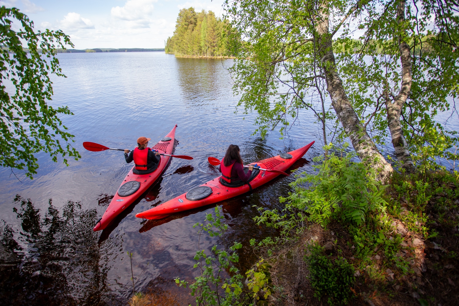 Kaksi henkilöä meloo punaisilla kajakeilla Kankarisvedellä