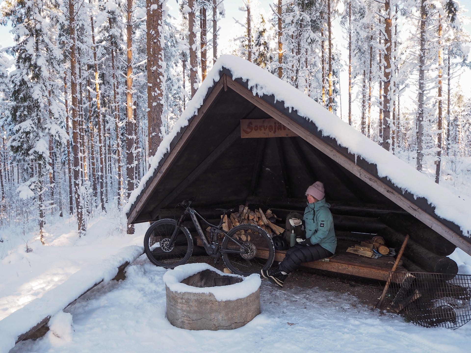 Pyöräilijä lepää laavulla talvella